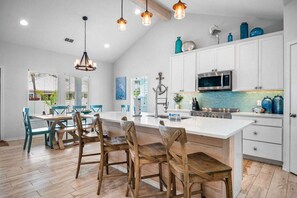 A modern kitchen with white cabinets, a large island, and pendant lighting. - Island Gem- 4 BR Golf Cart Accessible Boardwalk (Port Aransas)