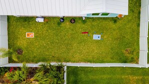 Un patio cercado con césped, un cobertizo pequeño y una zona de juegos con un tobogán.