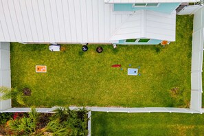 A fenced yard with a lawn, a small shed, and a play area with a slide. - Island Gem- 4 BR Golf Cart Accessible Boardwalk (Port Aransas)