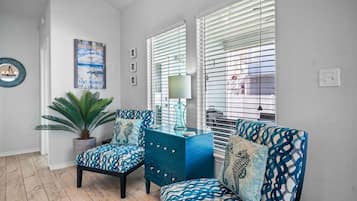 A room with two patterned chairs, a potted plant, a blue cabinet, and a wall-mounted lamp.