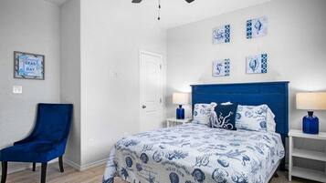 A bedroom with a bed, a chair, and artwork on the walls.