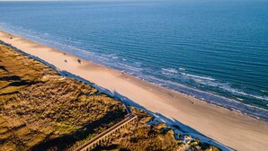 Un paisaje costero con una playa arenosa, un promontorio rocoso y una vista despejada del océano.