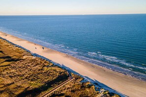 A coastal landscape with a sandy beach, a rocky outcrop, and a clear view of the ocean. - Island Gem- 4 BR Golf Cart Accessible Boardwalk (Port Aransas)