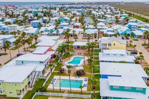 Un área residencial costera con casas, una piscina y una playa al fondo.