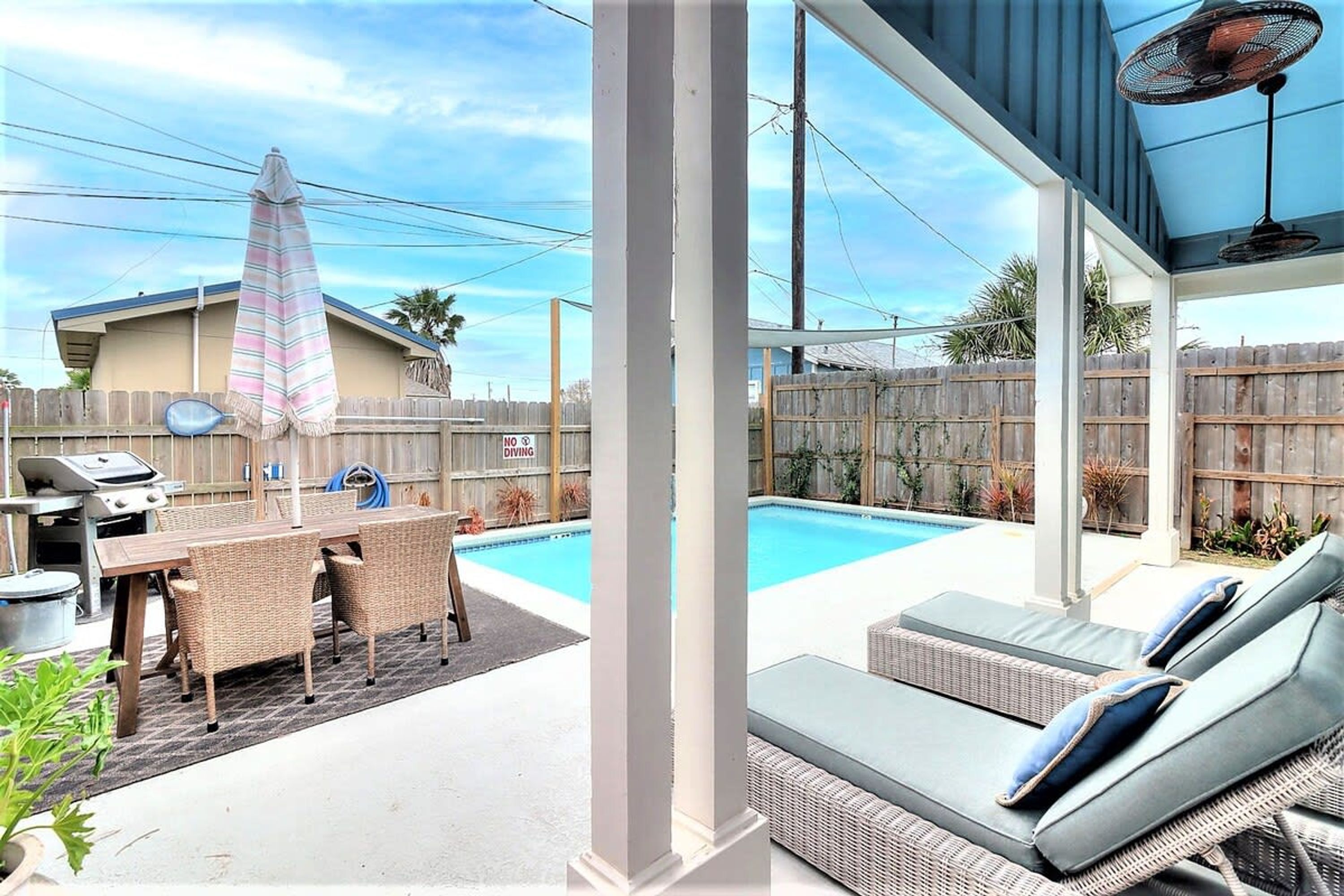 A backyard with a pool, a dining area with a grill, and a covered seating area.