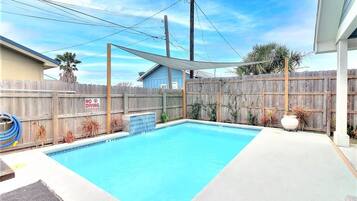 Piscina retangular com cerca de madeira e placa de 'NÃO MERGULHAR'.