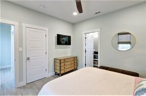Un dormitorio con cama, cómoda, televisor y espejo.