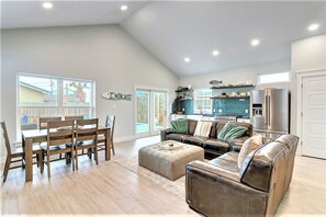 A spacious living room with a dining area, a kitchen with a blue backsplash, and a large window providing natural light. - La Puerta Rosada Private Pool Prime Location (Port Aransas)