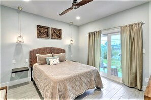 A bedroom with a bed, a ceiling fan, two wall-mounted lights, and a window with curtains. - La Puerta Rosada Private Pool Prime Location (Port Aransas)