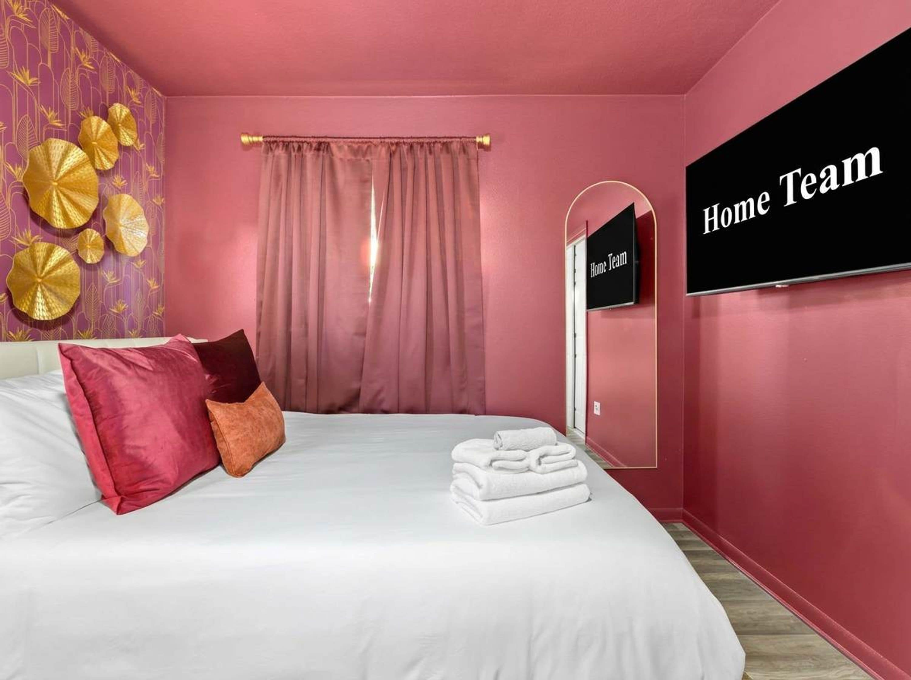 A bedroom with a bed, pillows, a TV, a curtain, and a wall-mounted sign.
