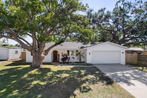A single-story house with a garage, surrounded by trees and a small lawn. - 5 Min to Beach Heated Pool Golf Sleeps 12 (Seminole)