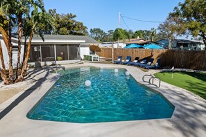 A rectangular swimming pool with clear blue water, surrounded by a wooden deck and a fenced area with lounge chairs. - 5 Min to Beach Heated Pool Golf Sleeps 12 (Seminole)