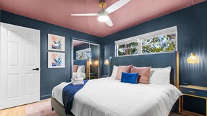 Une chambre à coucher avec un lit, des tables de chevet, un ventilateur de plafond et une fenêtre donnant sur un beau paysage.