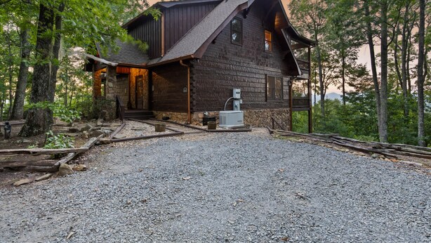A rustic cabin with a stone foundation, a sloped roof, and a gravel driveway. - Views for Miles Outdoor Fireplace Hot Tub (Morganton)