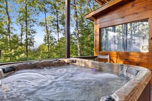Ein Whirlpool in einer Holzhütte, umgeben von Bäumen.