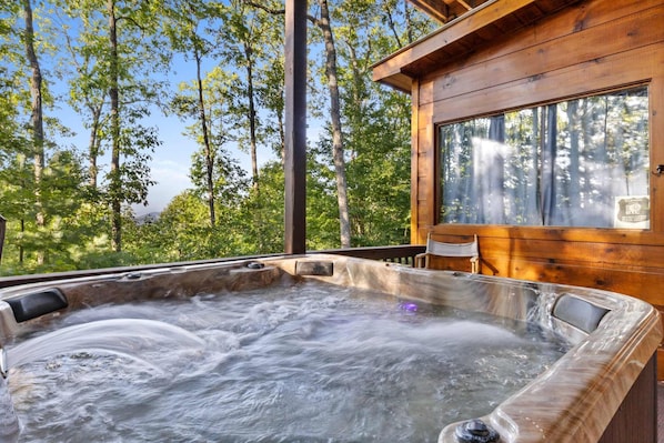 Un jacuzzi en una cabaña de madera rodeada de árboles.