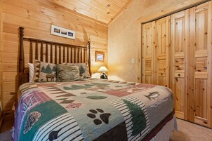 Ein Zimmer mit Holzwänden, einem Bett, einem Nachttisch und einer Tür.