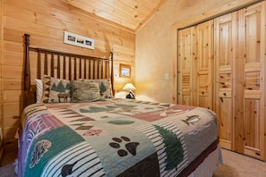 Una habitación con paneles de madera, una cama, una mesita de noche y una puerta.