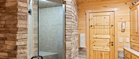 Un baño con cabina de ducha de vidrio, paredes y puerta de madera.