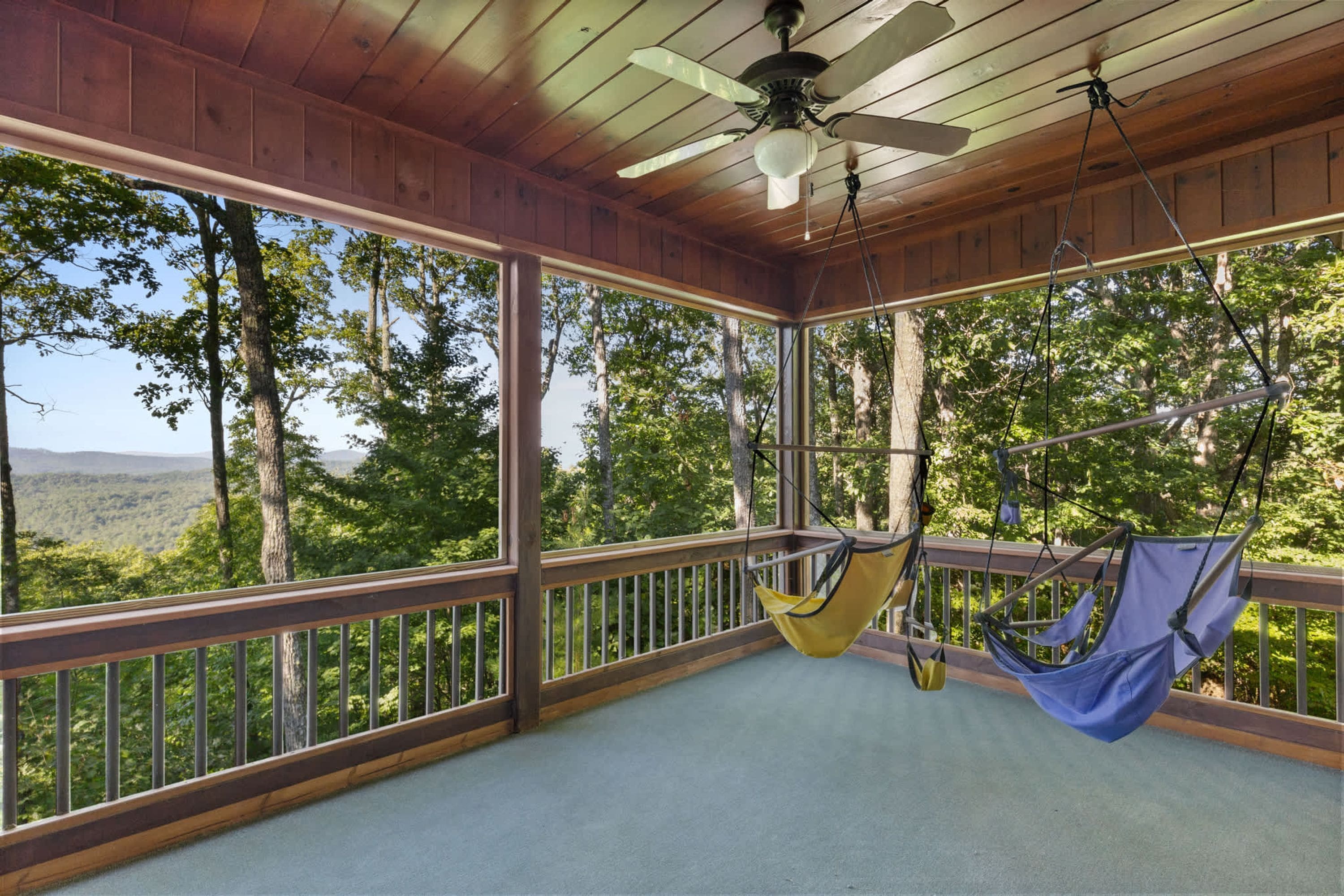 A wooden deck with a hammock and a ceiling fan.