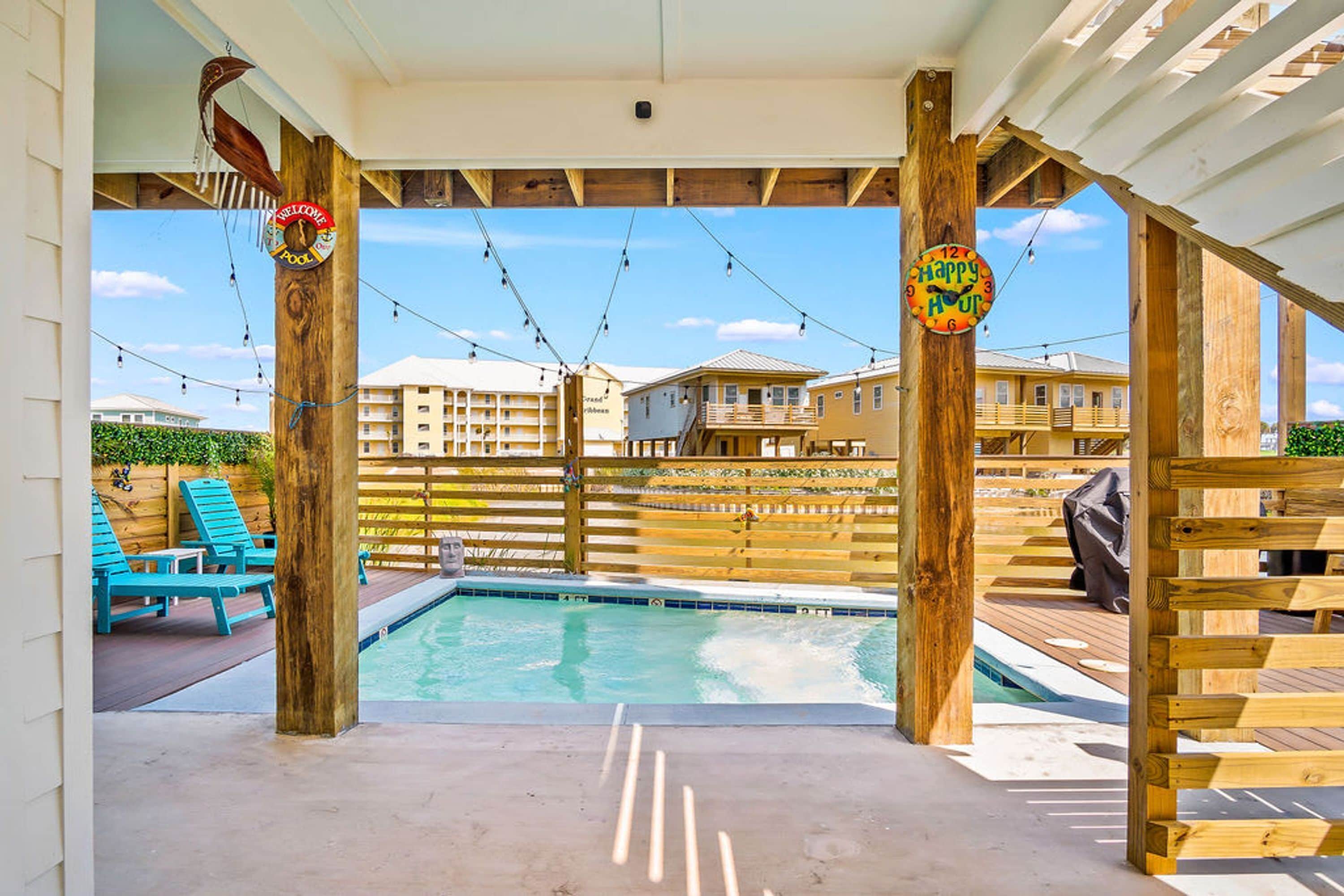 Un espace piscine doté d’une terrasse en bois, de chaises longues et offrant une vue sur les bâtiments en arrière-plan.