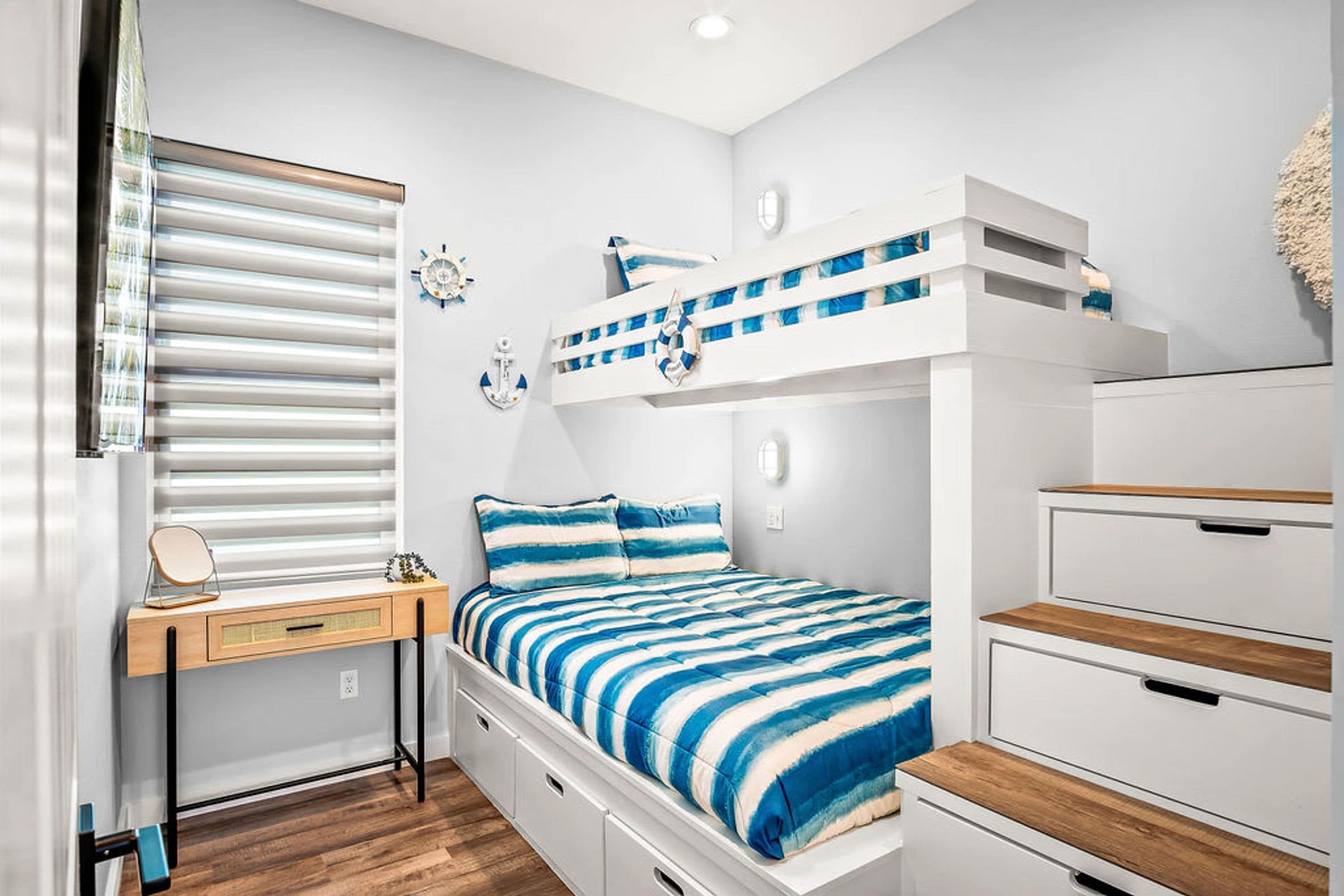 A bedroom with a bunk bed, a desk with a chair, and a dresser.