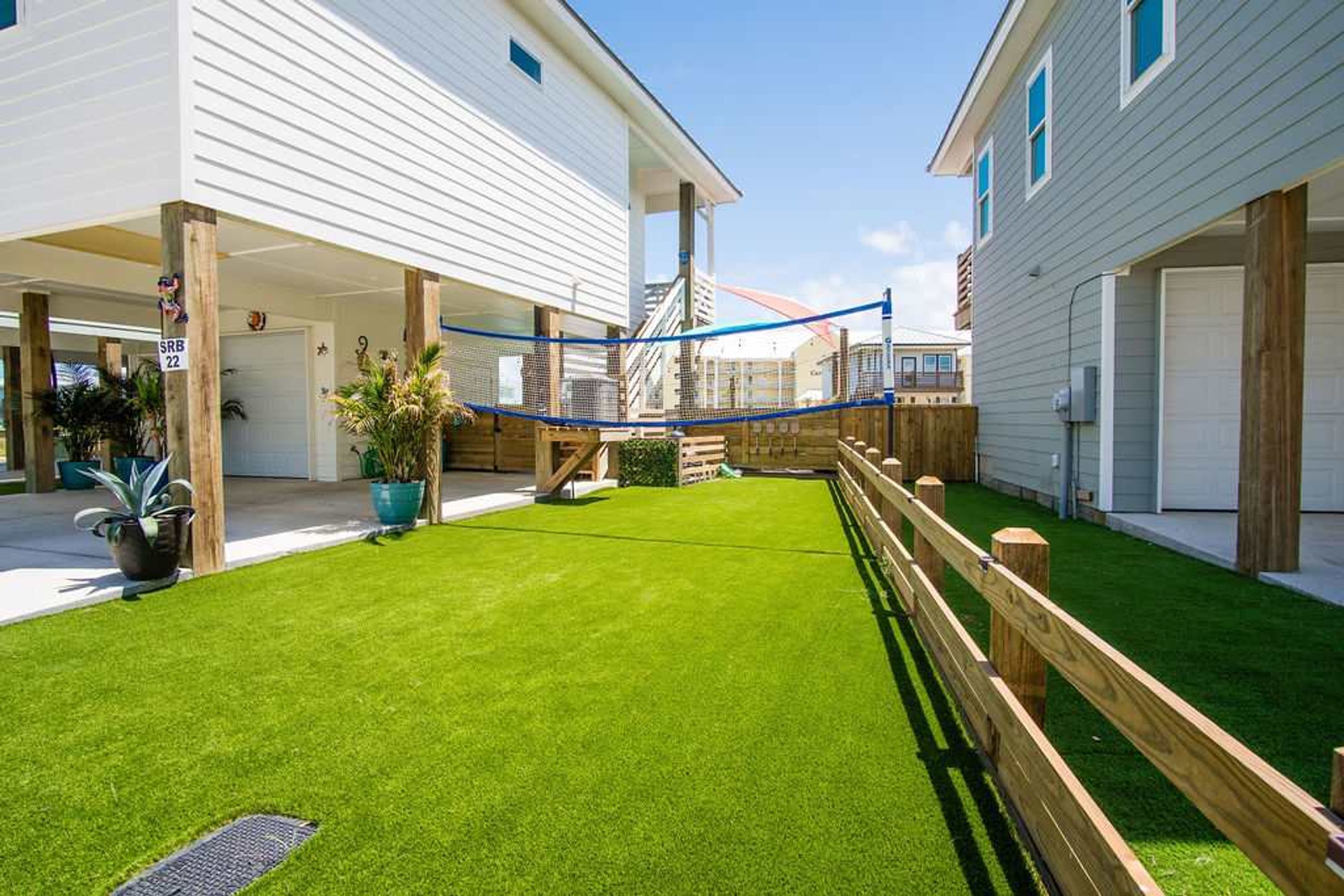 A residential area with two houses, a wooden fence, and a well-maintained lawn.