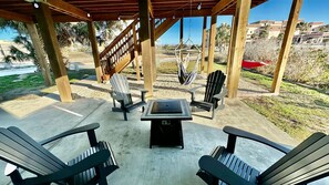An outdoor patio area with Adirondack chairs, a table, and a hammock. - Mustang Island Beach Side Sanctuary Game Room (Port Aransas)