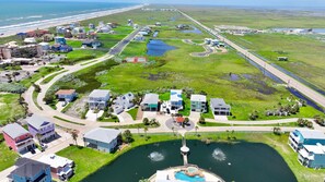 An aerial view of a coastal residential area with houses, a road, and a body of water. - Mustang Island Beach Side Sanctuary Game Room (Port Aransas)