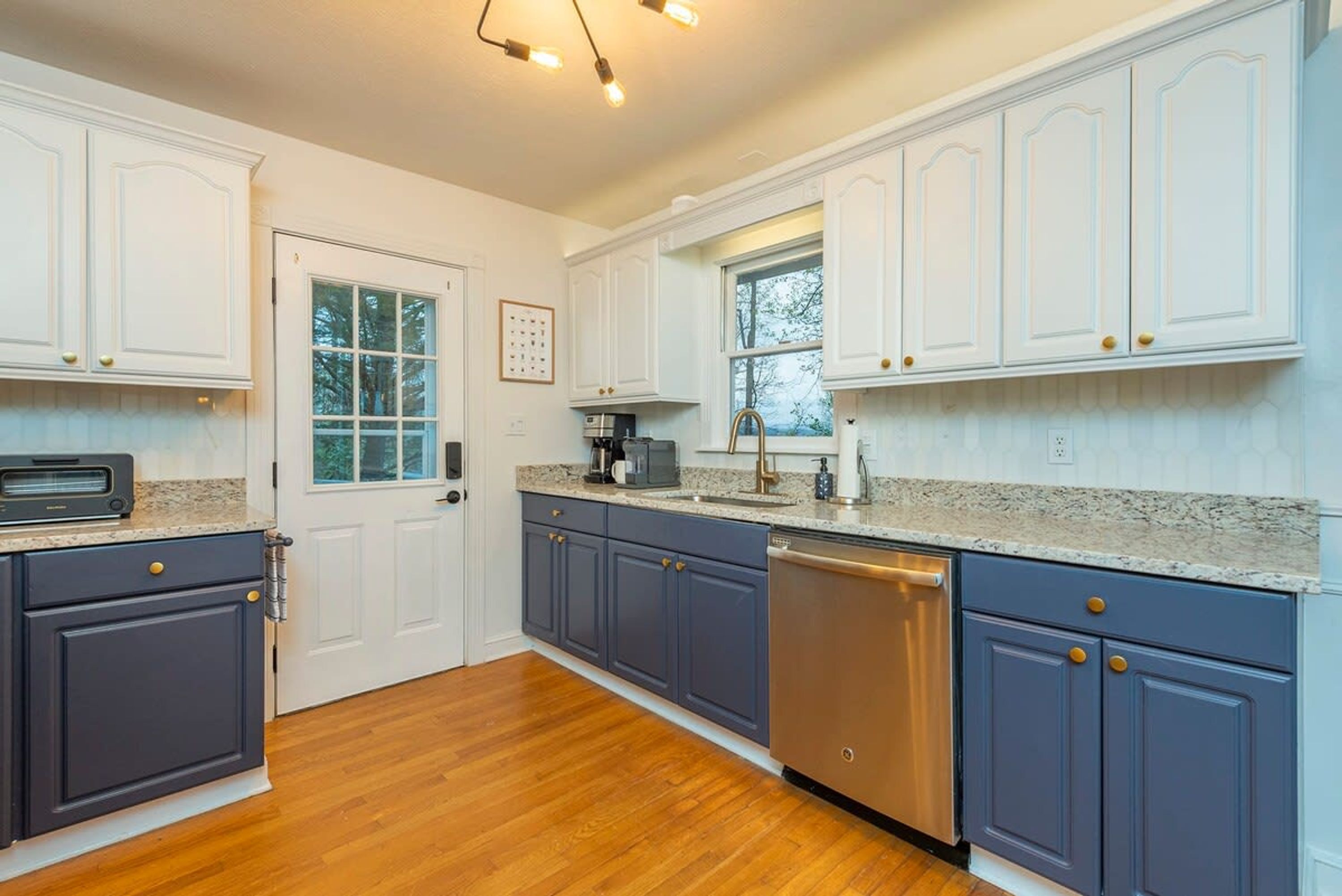 A kitchen with white cabinets, a dishwasher, and a window.