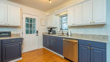 A kitchen with white cabinets, a dishwasher, and a window.