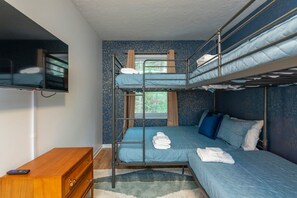 Habitació amb lliteres, televisió penjada a la paret i una petita còmoda de fusta.