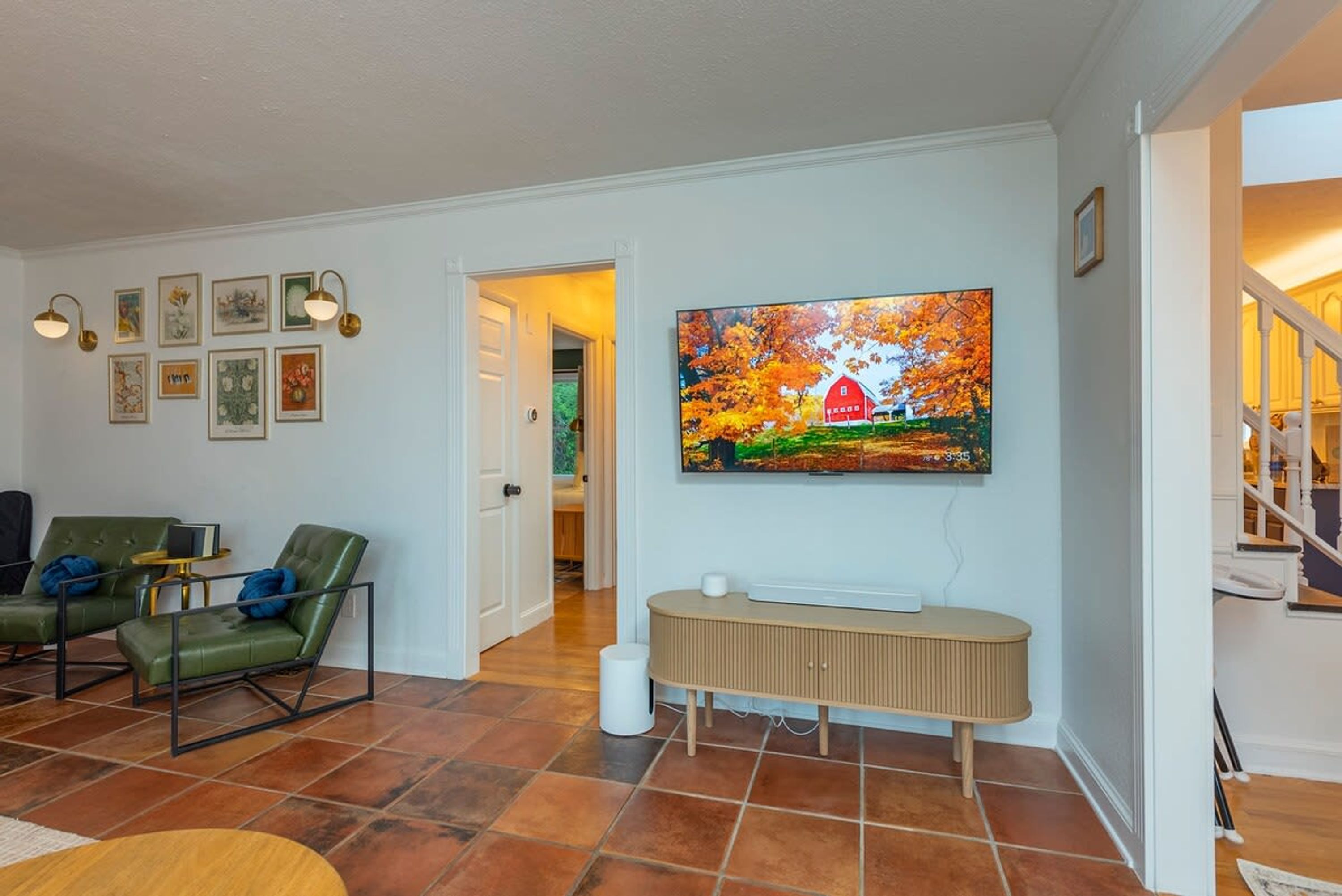 A living room with a television mounted on the wall, a green sofa, a coffee table, and a fireplace.