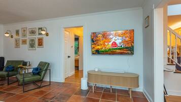 A living room with a television mounted on the wall, a green sofa, a coffee table, and a fireplace.