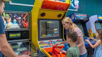 A family playing arcade games, including a Star Wars themed machine.