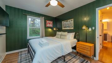 A bedroom with a bed, bedside table, nightstand, and a ceiling fan.