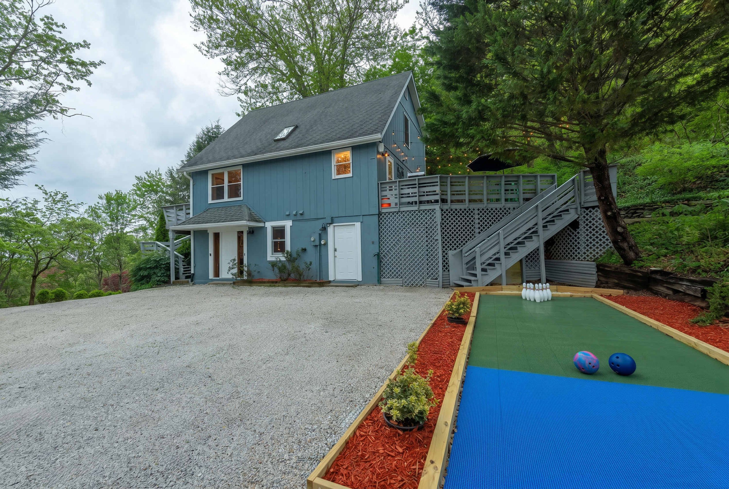 A two-story house with a gravel driveway and a front porch.