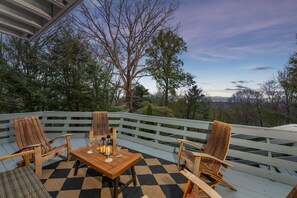 An outdoor patio with a checkered floor, wooden chairs, a table, and a view of trees and hills. - 25 Min to Asheville Game Room Fire Pit Hot Tub (Arden)