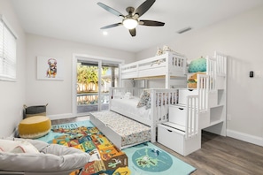 Habitación infantil con literas, ventilador de techo y un gran ventanal.