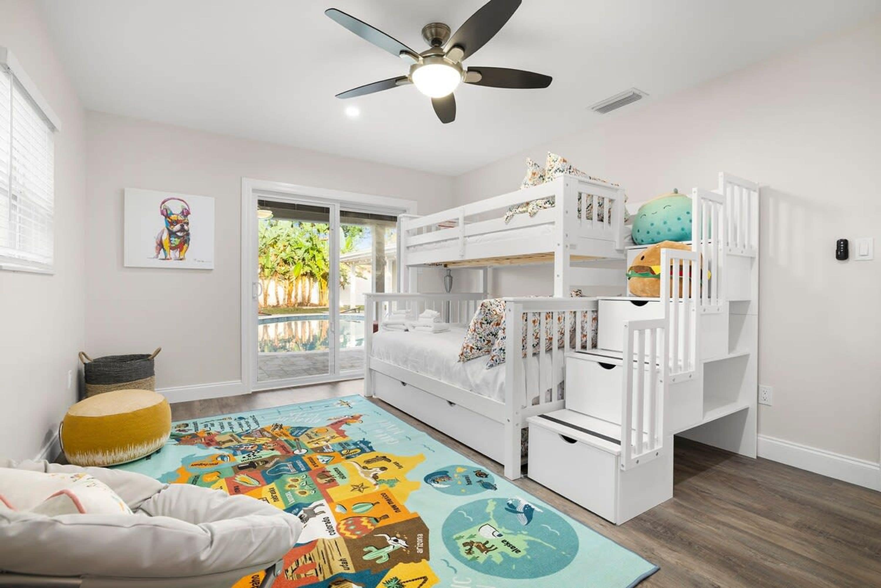 A child's bedroom with bunk beds, a ceiling fan, and a colorful rug.