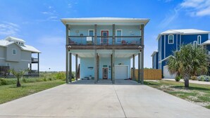 A two-story house with a balcony, a garage, and a front lawn. - Paradise Ahoy New Private Pool Decks With Views (Port Aransas)