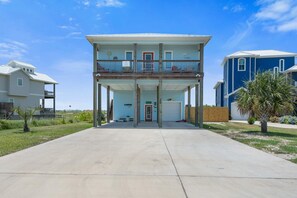 Ein zweistöckiges Haus mit Balkon, Garage und Rasen vor der Fassade.