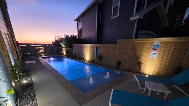 A backyard with a swimming pool, lounge chairs, and a wooden fence. - Paradise Ahoy New Private Pool Decks With Views (Port Aransas)