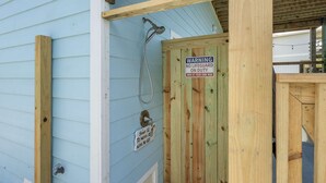 A wooden door with a warning sign, a shower hose, and a price sign for shower services. - Paradise Ahoy New Private Pool Decks With Views (Port Aransas)