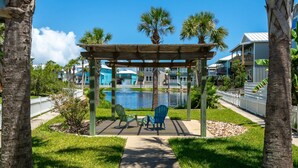 A gazebo with two chairs, a pond, and a view of a residential area with houses. - Paradise Ahoy New Private Pool Decks With Views (Port Aransas)