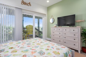 A bedroom with a bed, a television, a dresser, and a balcony with a chair. - Paradise Ahoy New Private Pool Decks With Views (Port Aransas)