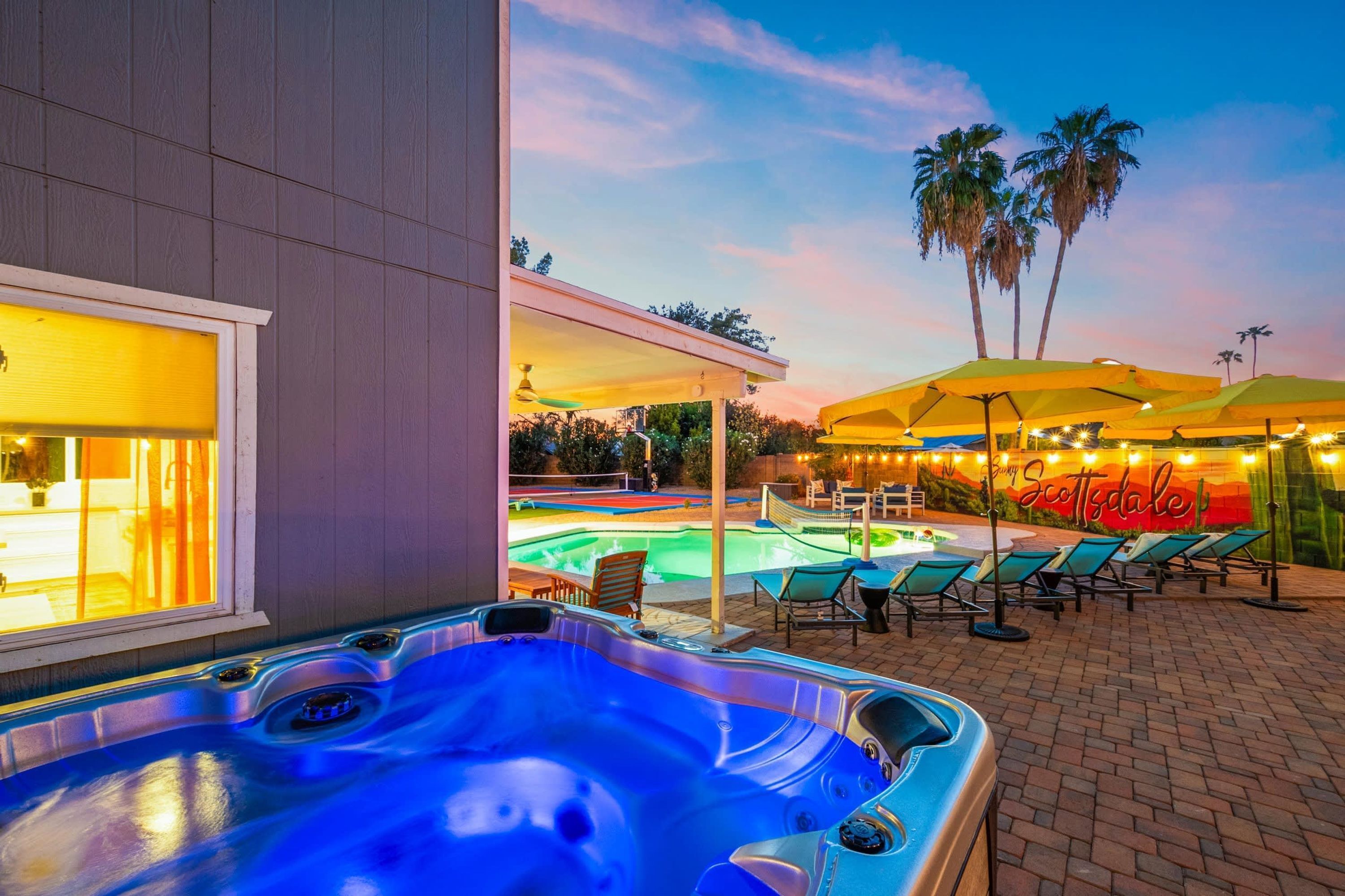 Un bain à remous avec piscine, un espace salon extérieur et une vue sur le coucher de soleil.