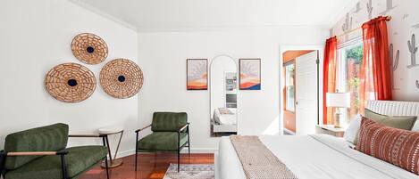 A bedroom with a bed, two chairs, a small table, and a rug.