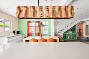 Une cuisine moderne avec un coin repas, un escalier et un mur végétal agrémenté d’œuvres d’art.