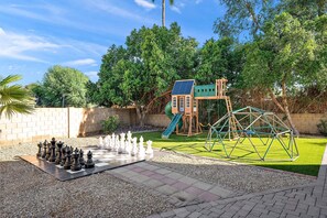 Ein Spielplatz mit Rutsche, Klettergerüst und einem Schachbrett auf dem Boden.